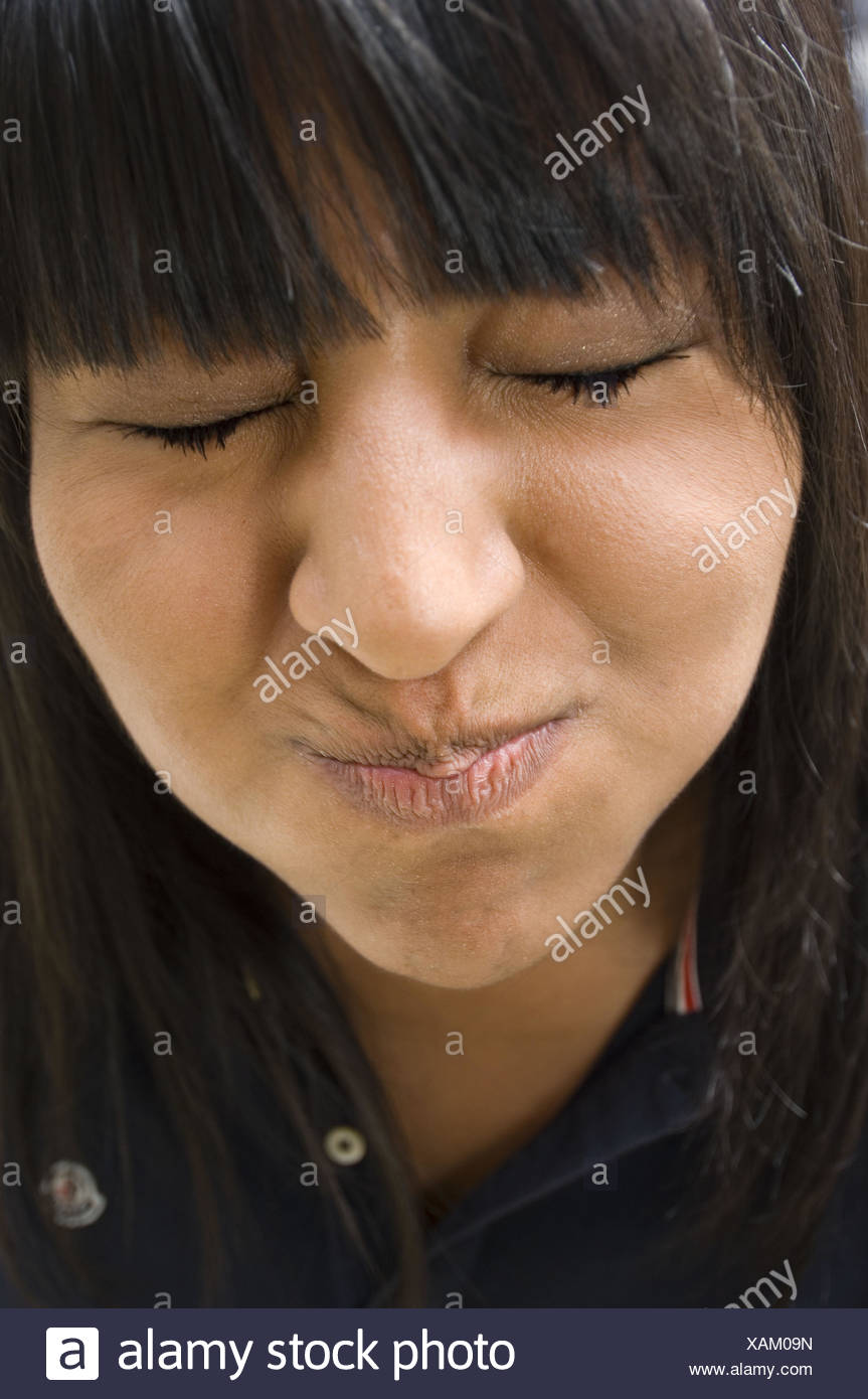 El rostro de un adolescente que hace muecas abultadas mejillas y cerró los ojos Foto de stock