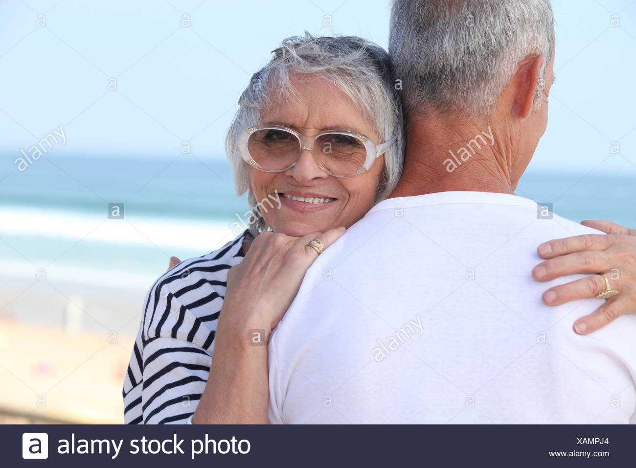 Pareja de ancianos abrazarse por una playa Foto de stock