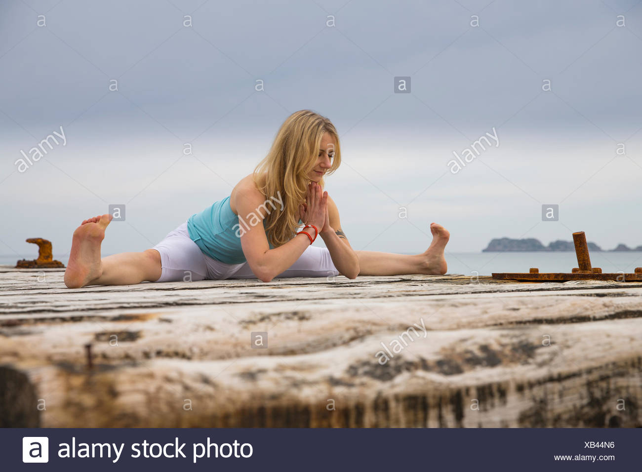 Mitad mujer adulta con manos juntas practicando yoga en Mar del muelle de madera Foto de stock