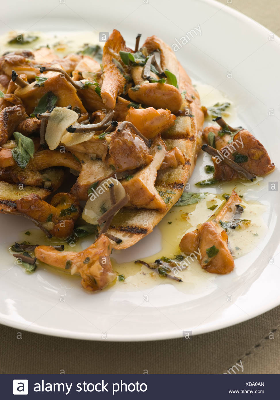 Setas salteadas en mantequilla de ajo con Char Baguette asada y trufa negra Foto de stock