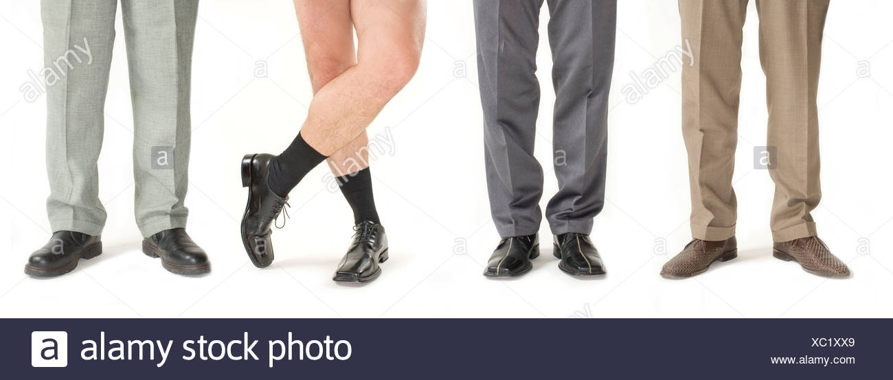 Cuatro ejecutivos de pie en una fila, uno sin pantalones, detalle de piernas Foto de stock