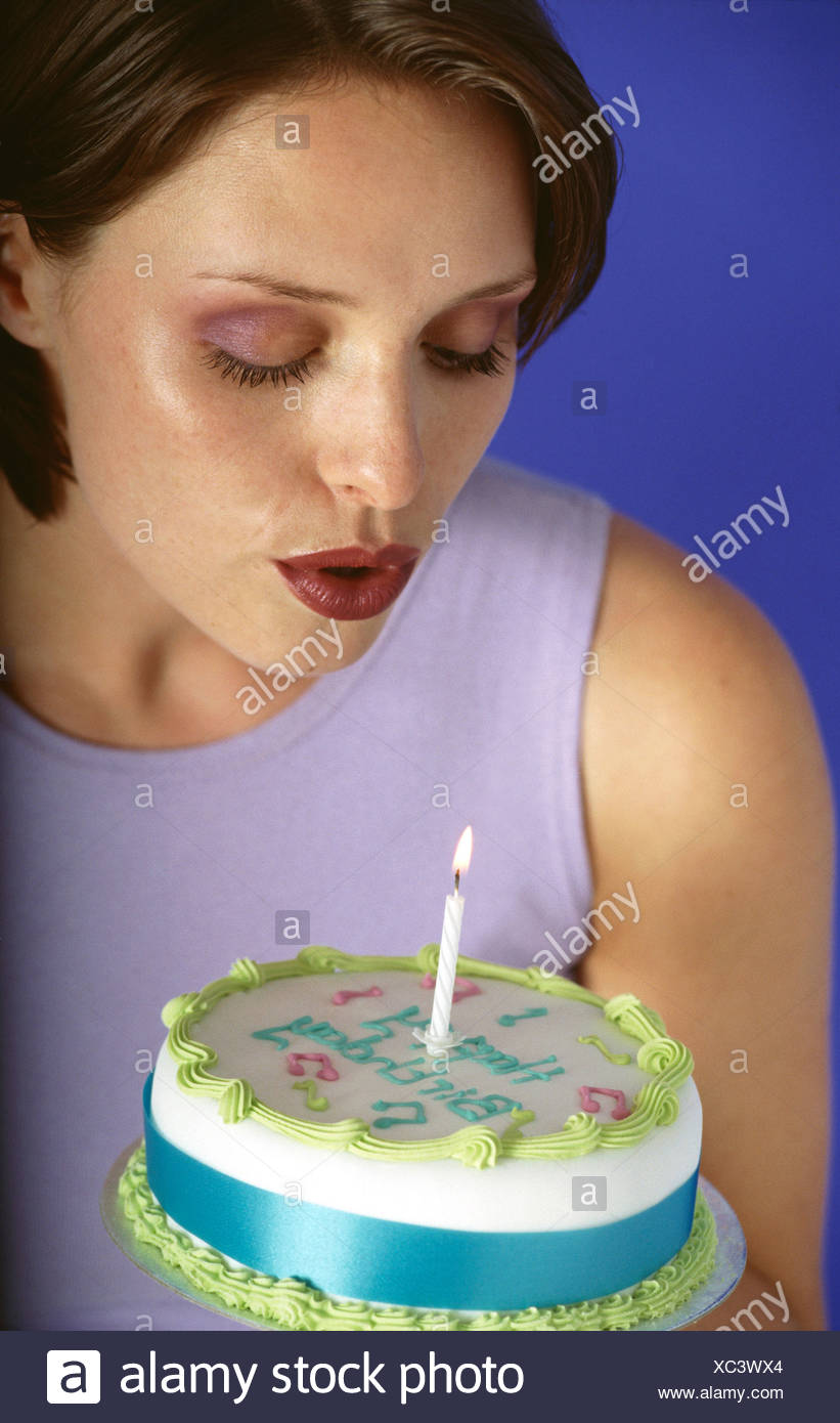 Hembra Morena Cabello Corto Vistiendo Un Top Lila Sosteniendo Un Pastel De Cumpleanos Una Vela En Frente De Ella Soplando A Vela Buscando Fotografia De Stock Alamy