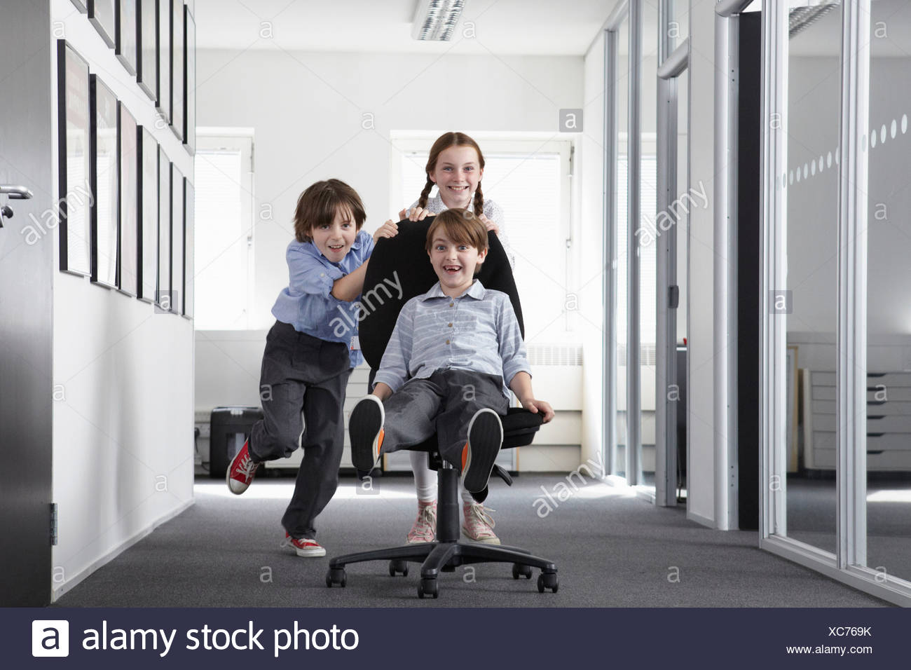 Tres niños jugando en el pasillo de oficina en silla de oficina Foto ... Tres niños jugando en el pasillo de oficina en silla de oficina Foto ...