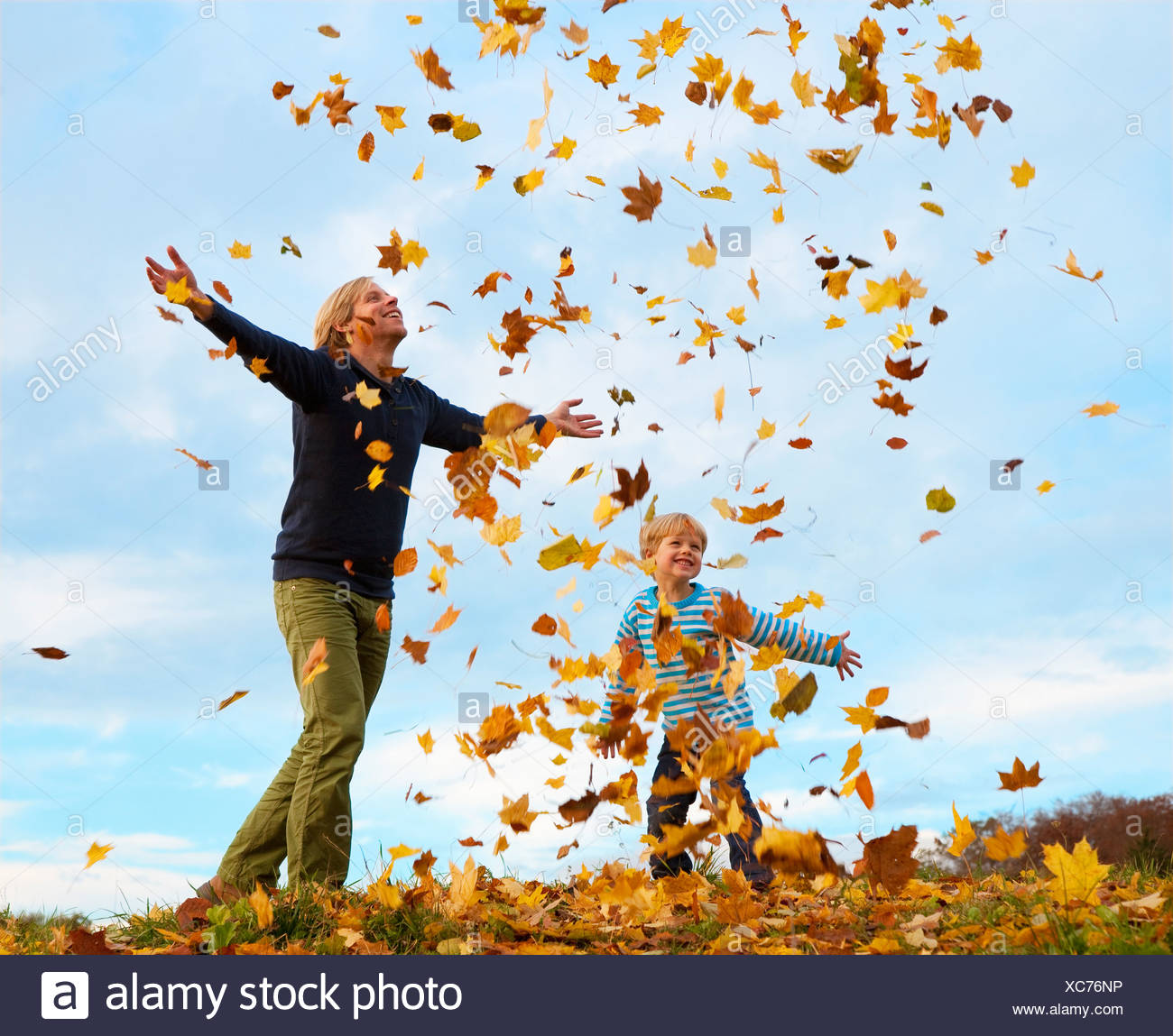 Padre e hijo jugando en hojas de otoño Foto de stock