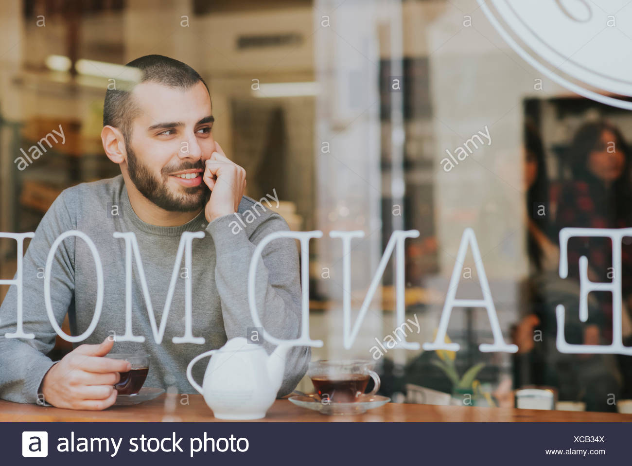 Joven sentado en la cafetería, ver a través de la ventana Foto de stock