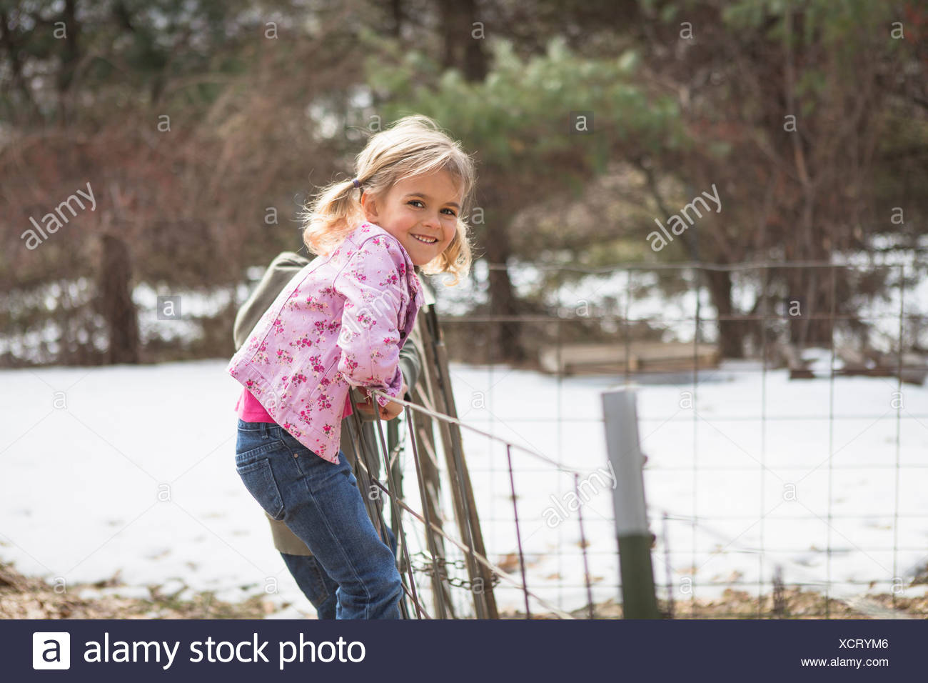 Joven escalando alambrada en el campo Foto de stock