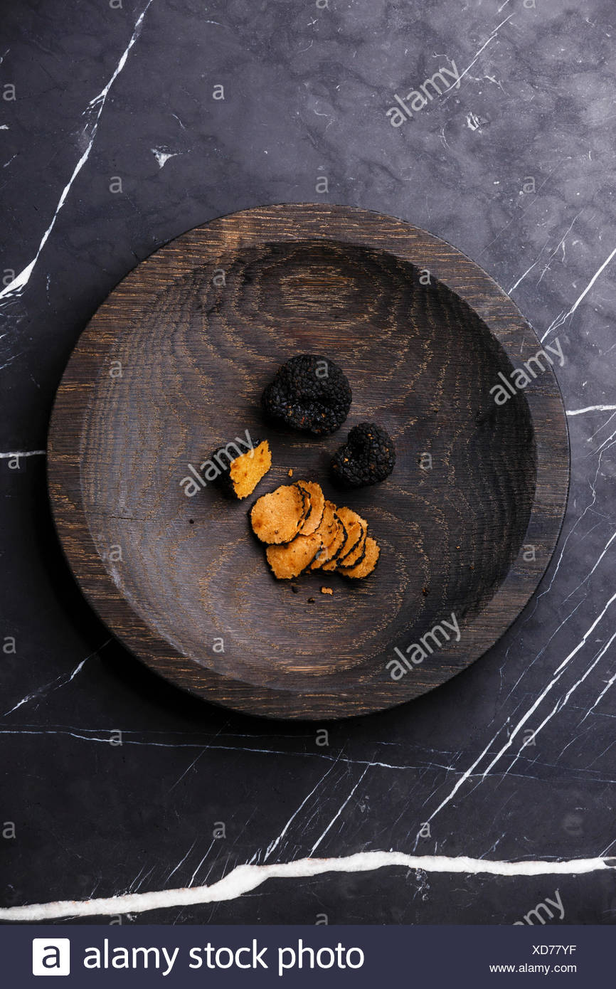 Placa de madera en la trufa negra sobre fondo de mármol oscuro Foto de stock