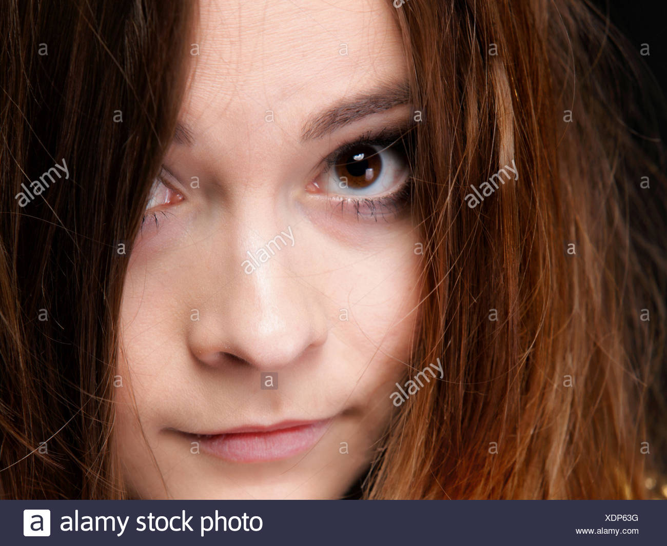 Close-up retrato de una bella mujer cubre el rostro por largos pelos marrones Foto de stock