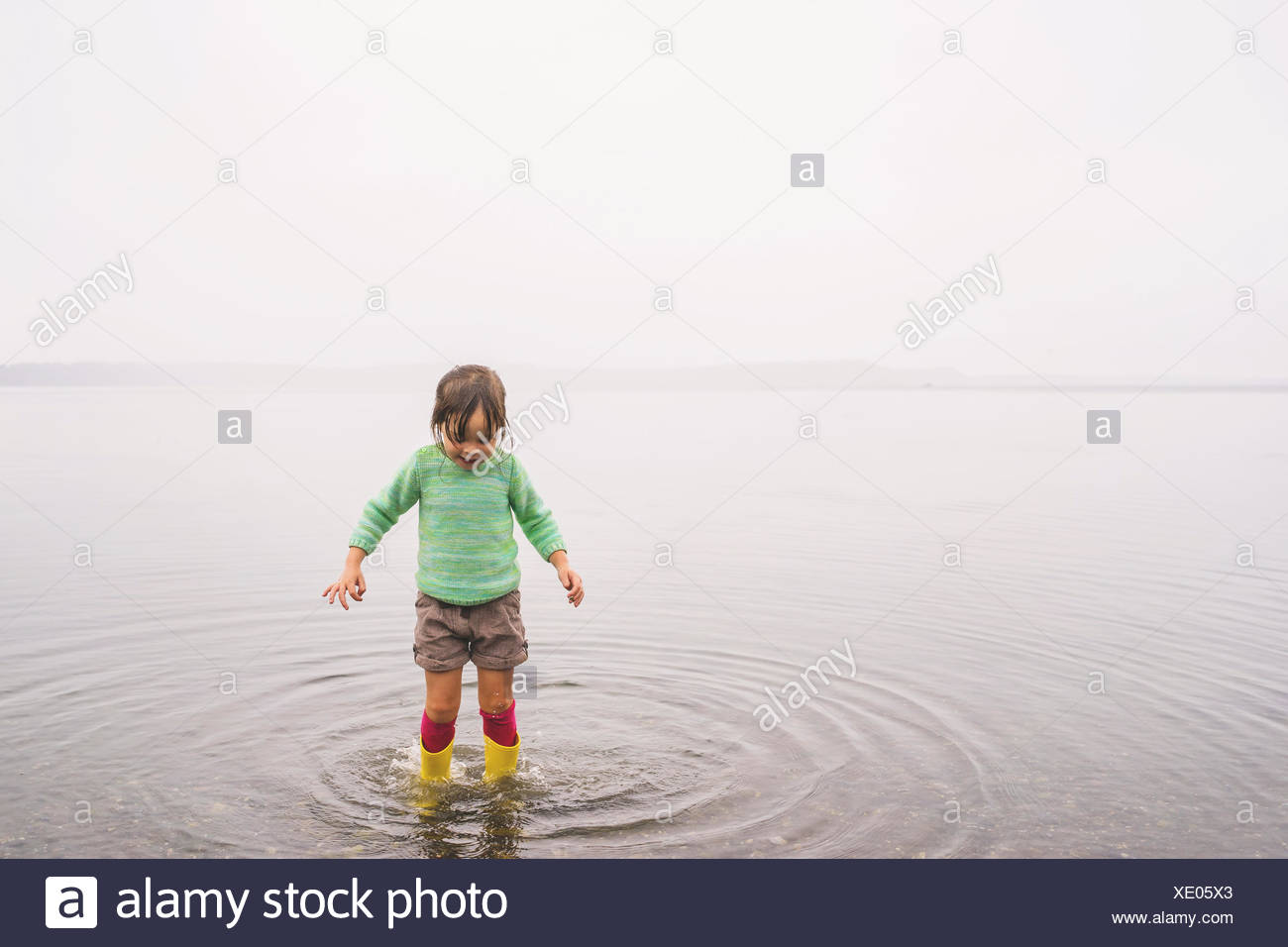 Chica de pie en aguas poco profundas, Haciendo ondulaciones Foto de stock