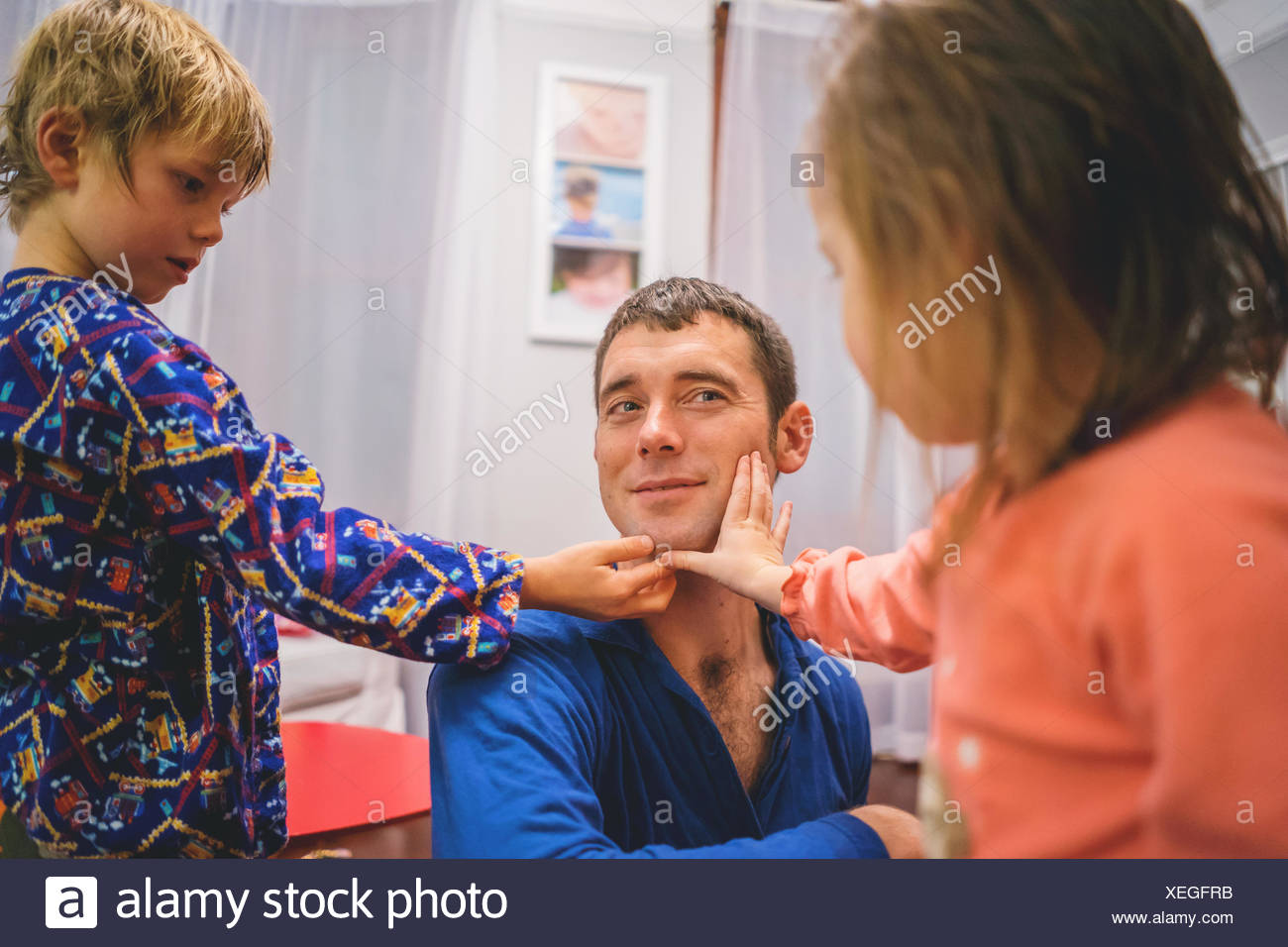 Chico y chica tocar cara afeitada del hombre. Foto de stock