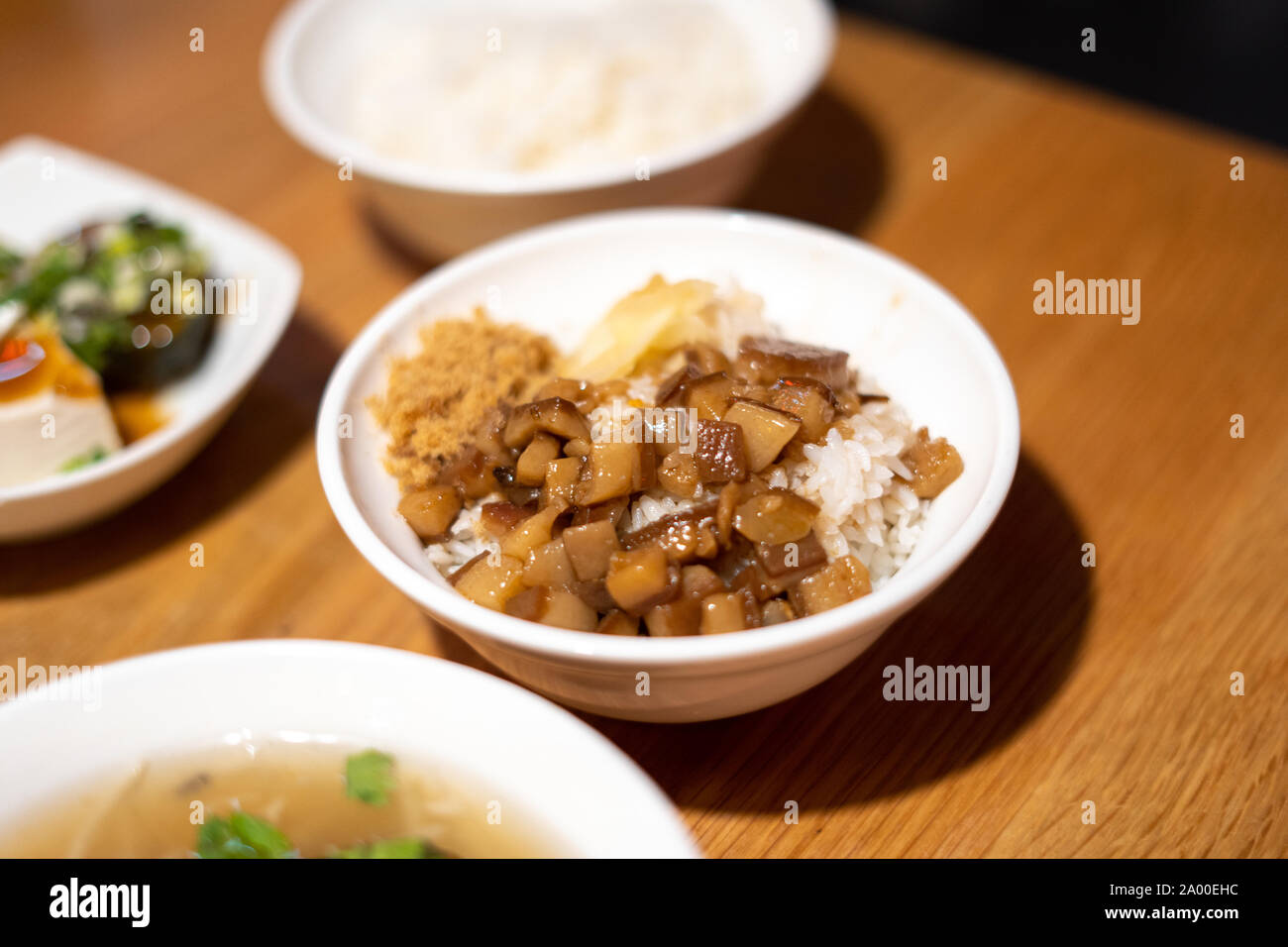 Flanc de porc braisé taïwanais sur le riz dans un bol blanc sur une table de restaurant en bois. Lu Rou Fan 滷肉飯 Taiwans est l'un des plats nationaux les plus populaires Banque D'Images