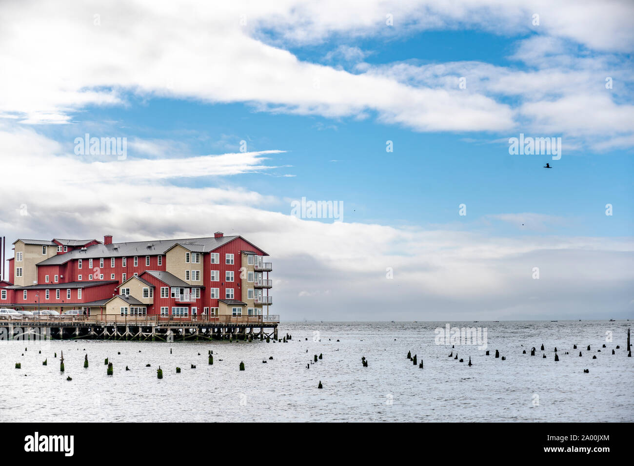Bâtiment en bois rouge sur l'ancien quai de pêche avec des piles de bois qui dépasse de l'eau à l'échelle de l'embouchure de la rivière Columbia, dans le Pacifique sur la ville Astoria Banque D'Images