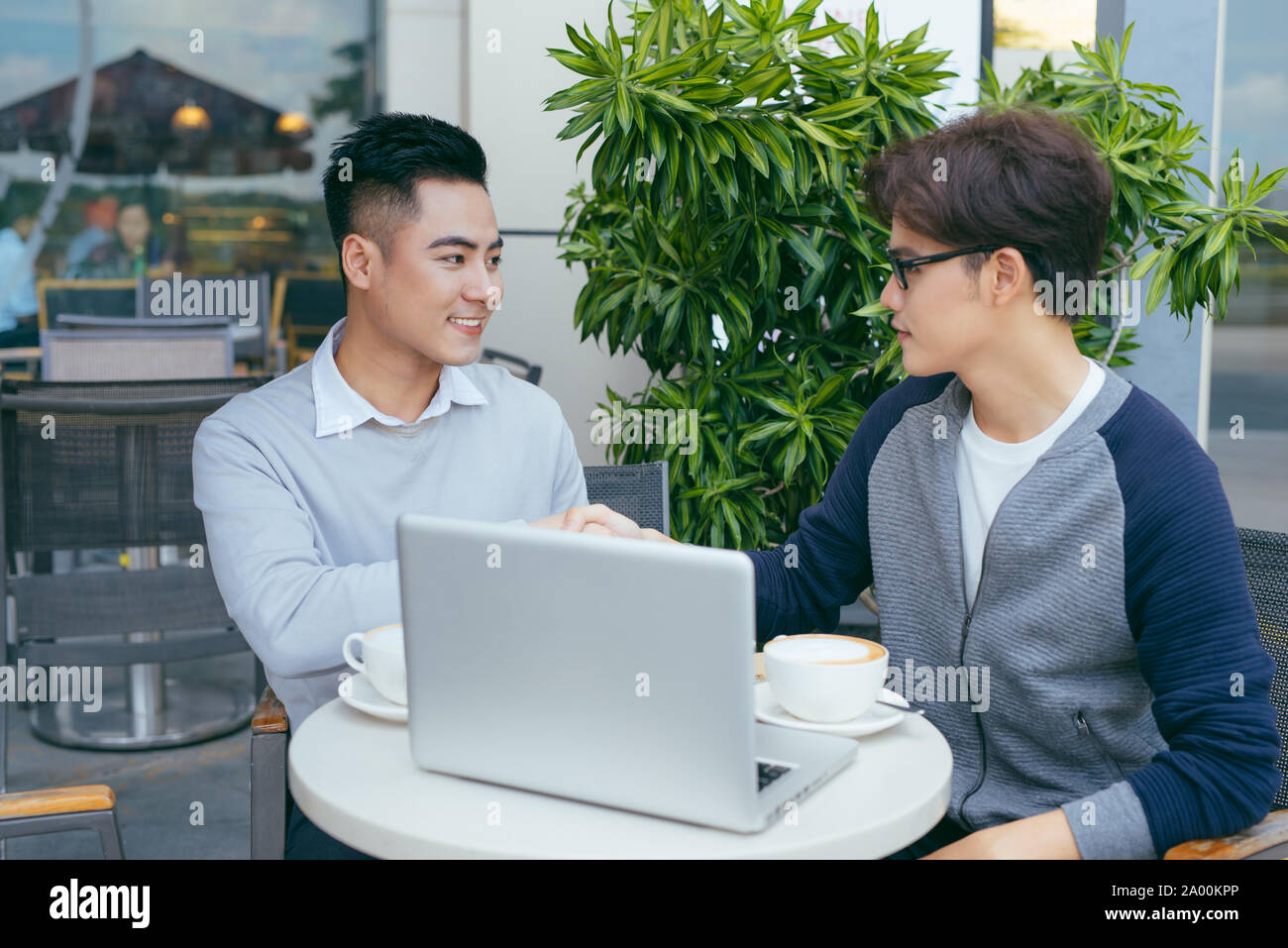 Deux jeunes hommes sont en pleine discussion dans un café. - Image Banque D'Images