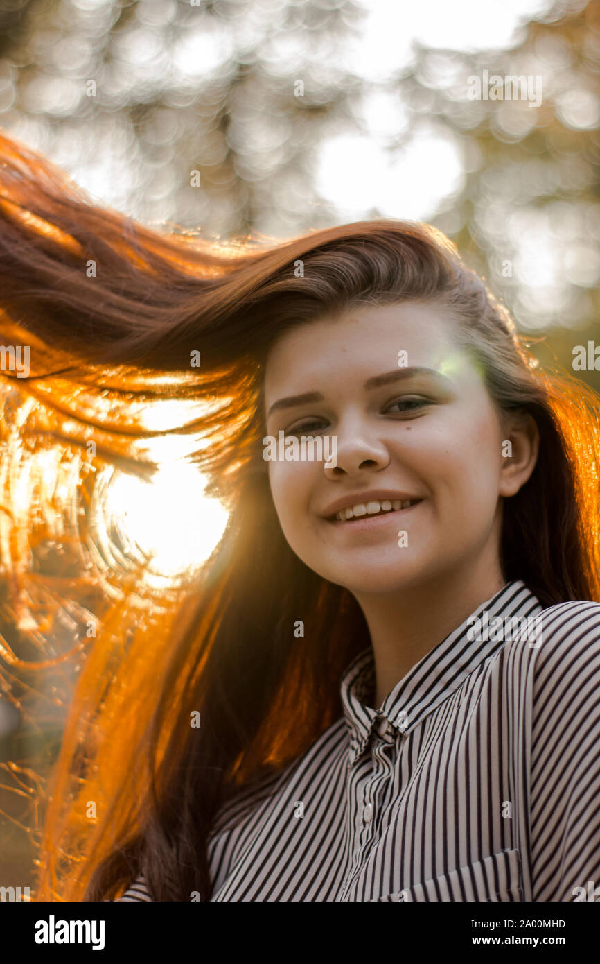 Portrait d'une belle fille brune dont le coucher de soleil brille dans ses cheveux Banque D'Images