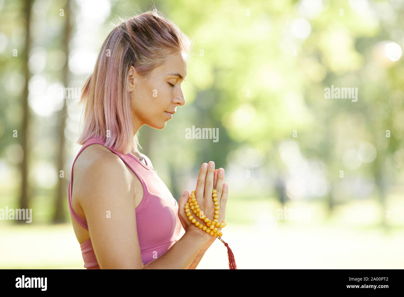 Side view of young woman standing calme avec ses yeux fermés et à l'écoute de son esprit pendant la méditation en plein air Banque D'Images