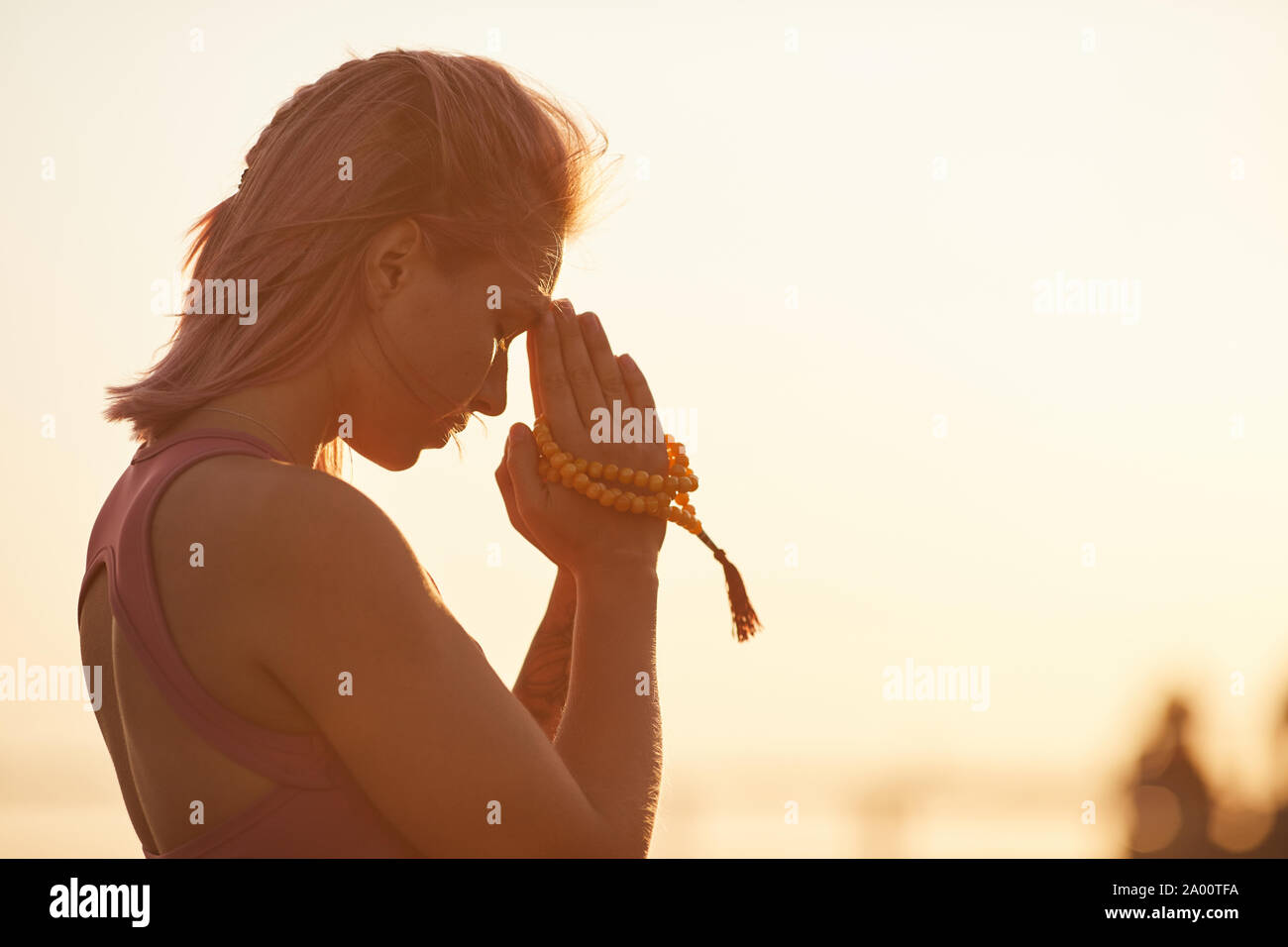 Jeune femme avec de courts cheveux blonds faisant du yoga et la méditation pendant le coucher du soleil sur l'air frais Banque D'Images