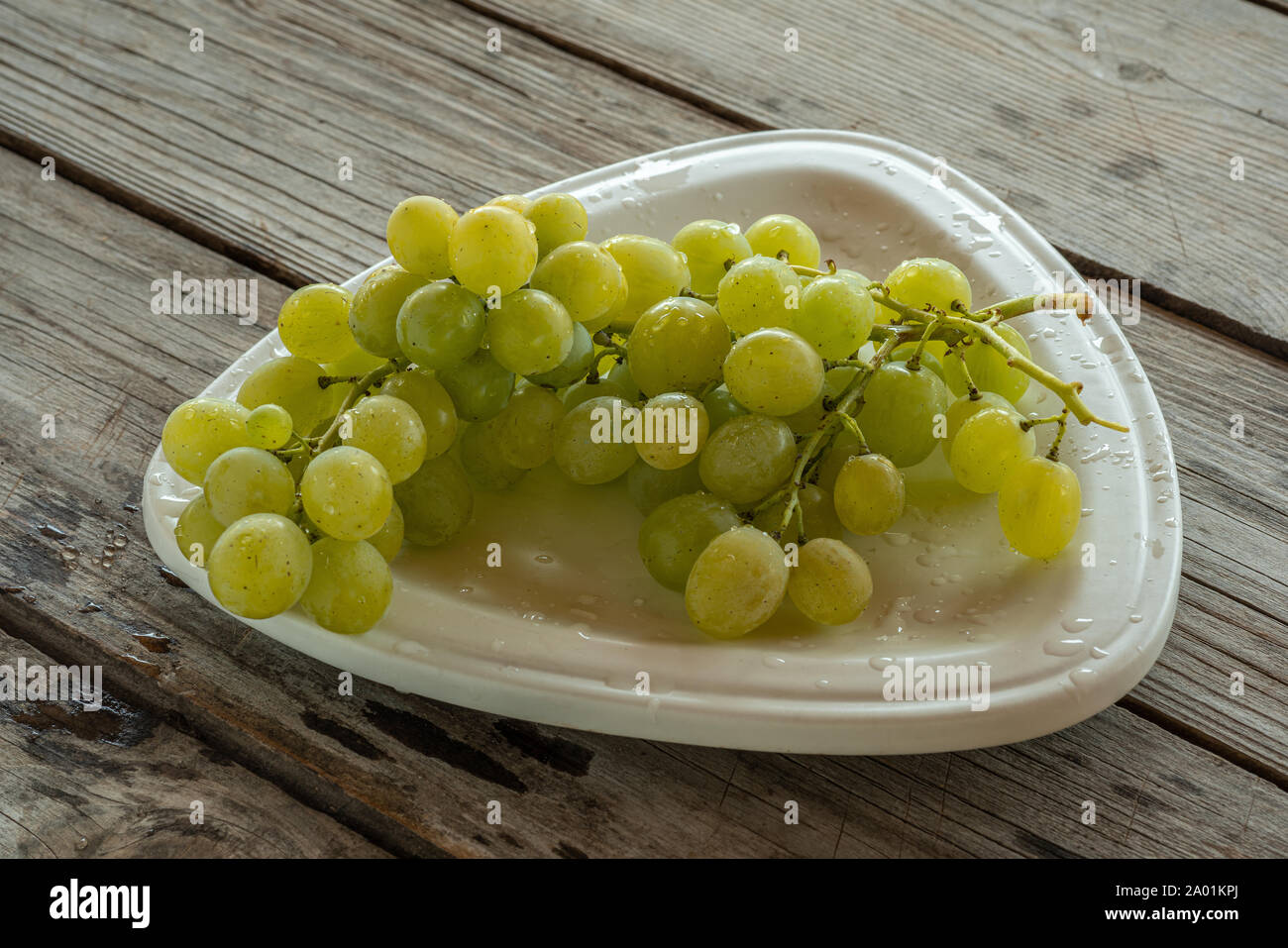 Bouquet de raisins blancs avec des gouttes d'eau sur la plaque Banque D'Images