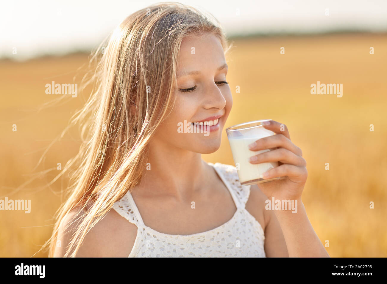 Le lait de consommation à partir de la fille de verre sur le champ de céréales Banque D'Images