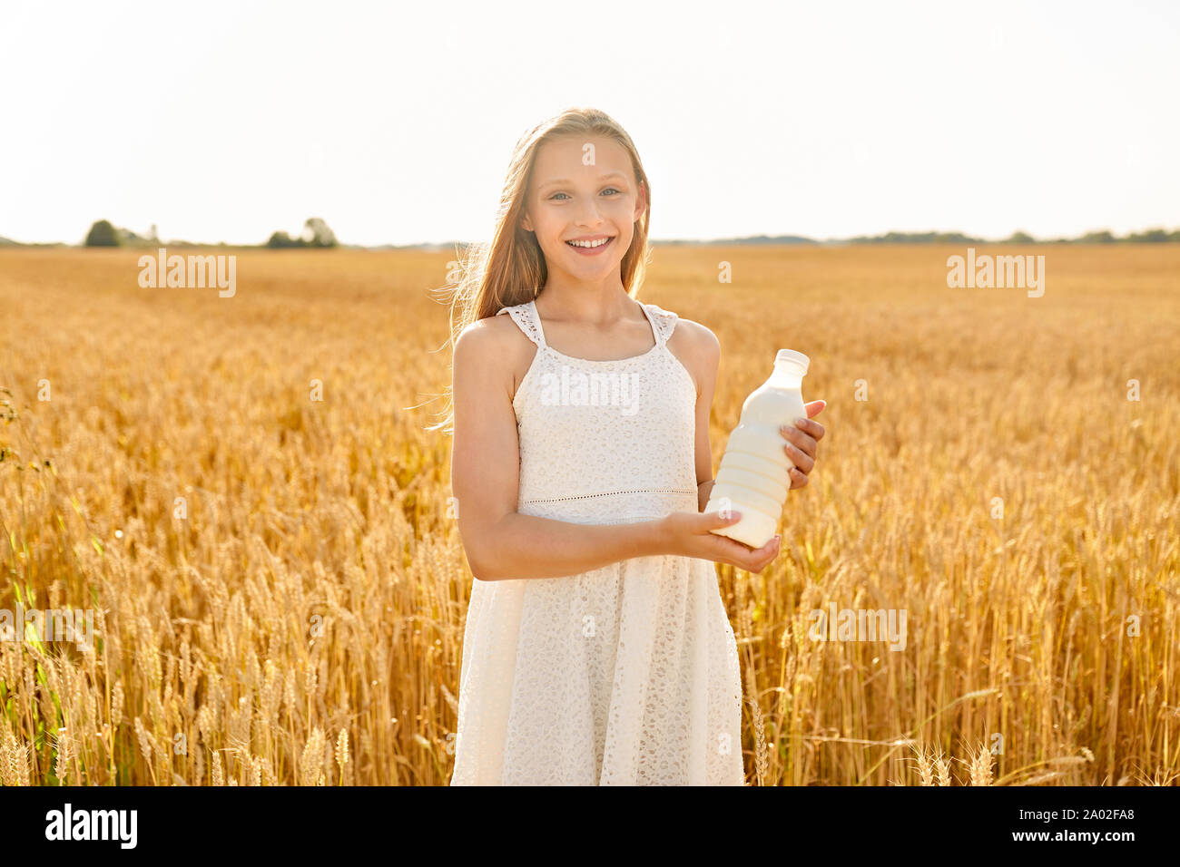 Happy girl avec une bouteille de lait dans le champ de céréales Banque D'Images