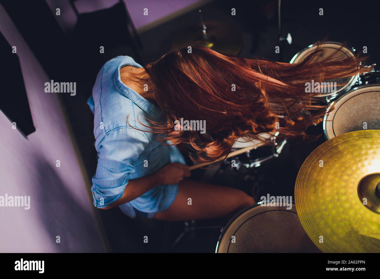 Photographie d'un batteur de femmes jouant un ensemble de batterie sur scène. Banque D'Images