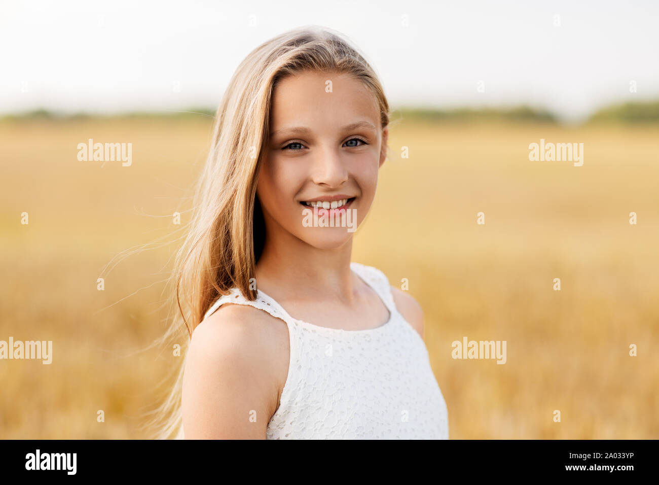Souriante jeune fille sur le champ de céréales en été Banque D'Images