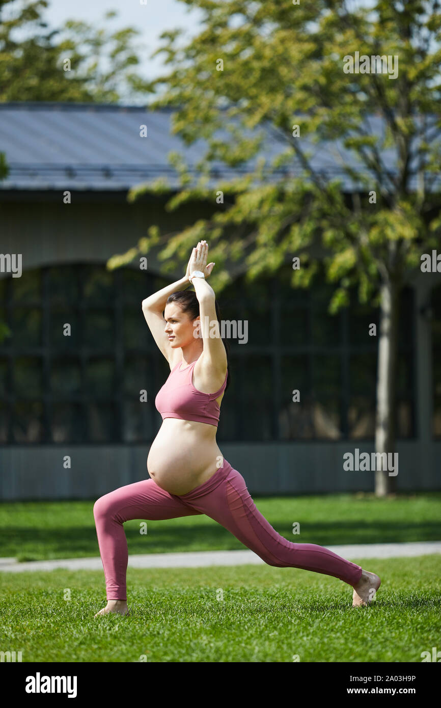 Belle Jeune femme enceinte debout dans poser et faire du yoga dans le parc Banque D'Images