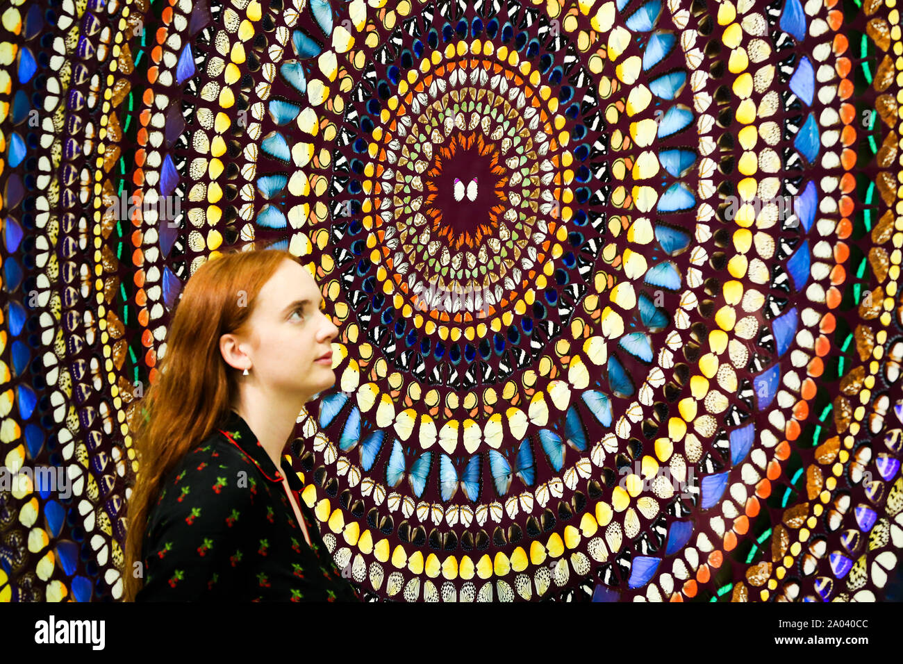 Femme regarde 'tranquillité' par l'artiste Damien Hirst composé d'ailes de papillon et brillant du ménage sur toile lors de l'exposition au White Cube à Londres. Banque D'Images