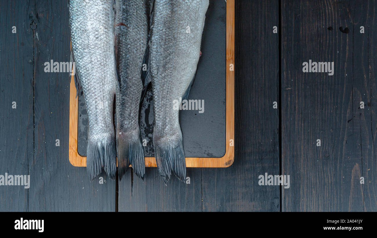 Poissons de mer frais sur une planche à découper sur une table en bois sombre. Bannière alimentaire Banque D'Images