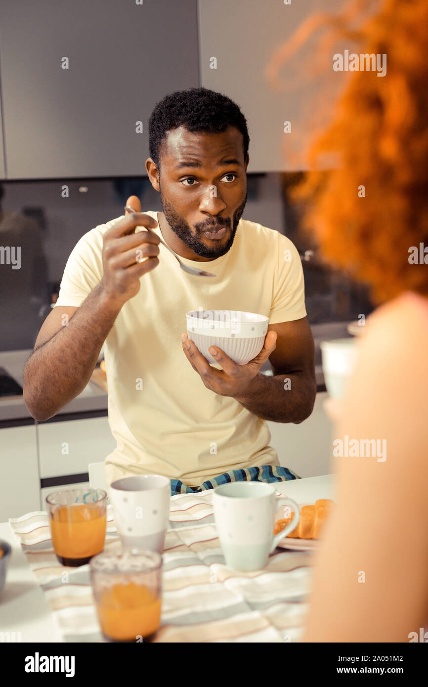 Petit déjeuner sain. L'homme attentif soulevant les sourcils tout en étant surpris avec news Banque D'Images