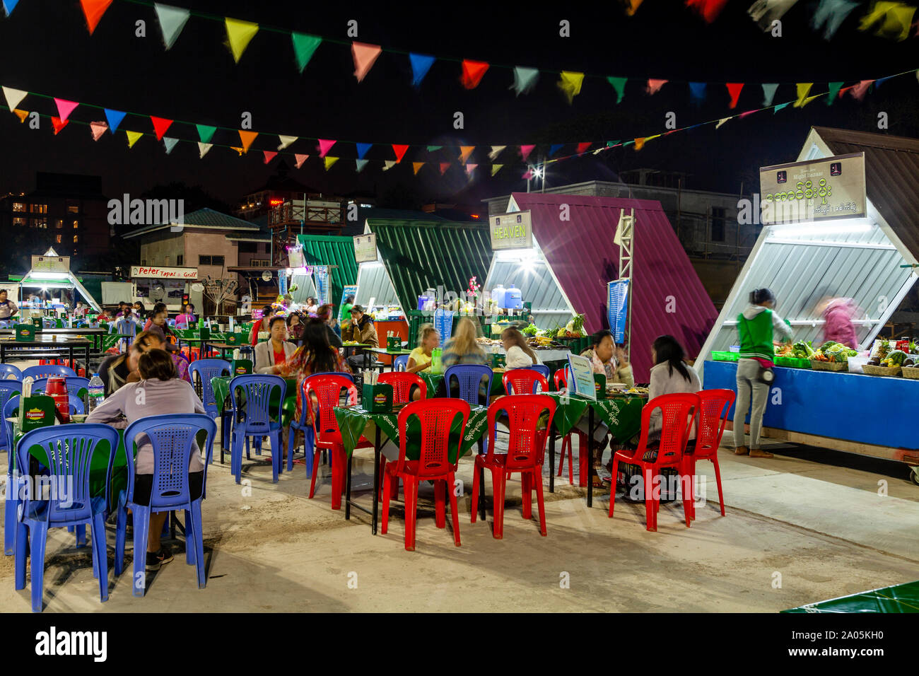 La population locale et les touristes de manger des aliments de rue à des tables dans le marché de nuit, Nyaung Shwe, le lac Inle, l'État de Shan, Myanmar. Banque D'Images