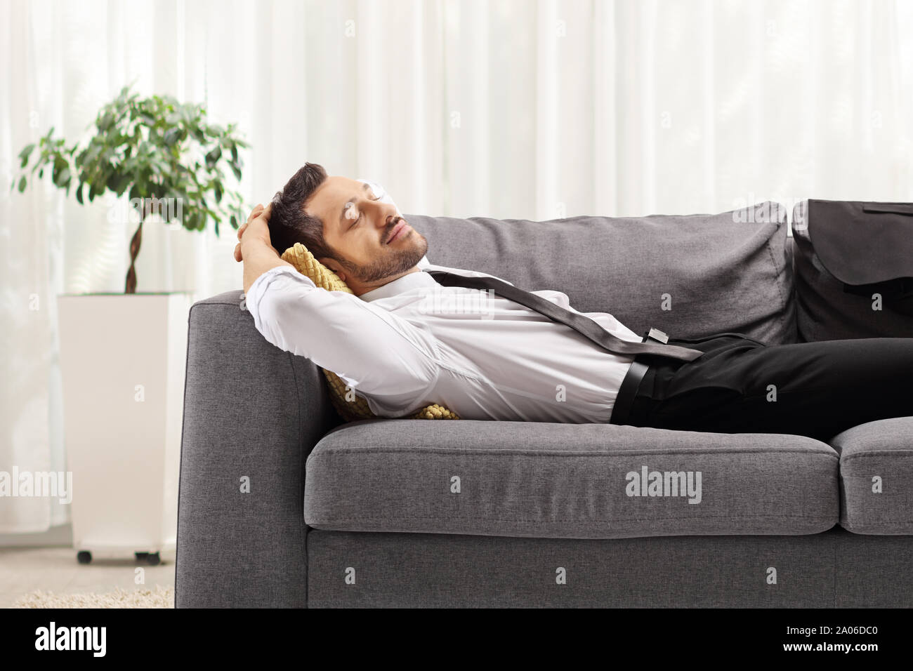 Businessman resting on gris canapé à la maison Banque D'Images