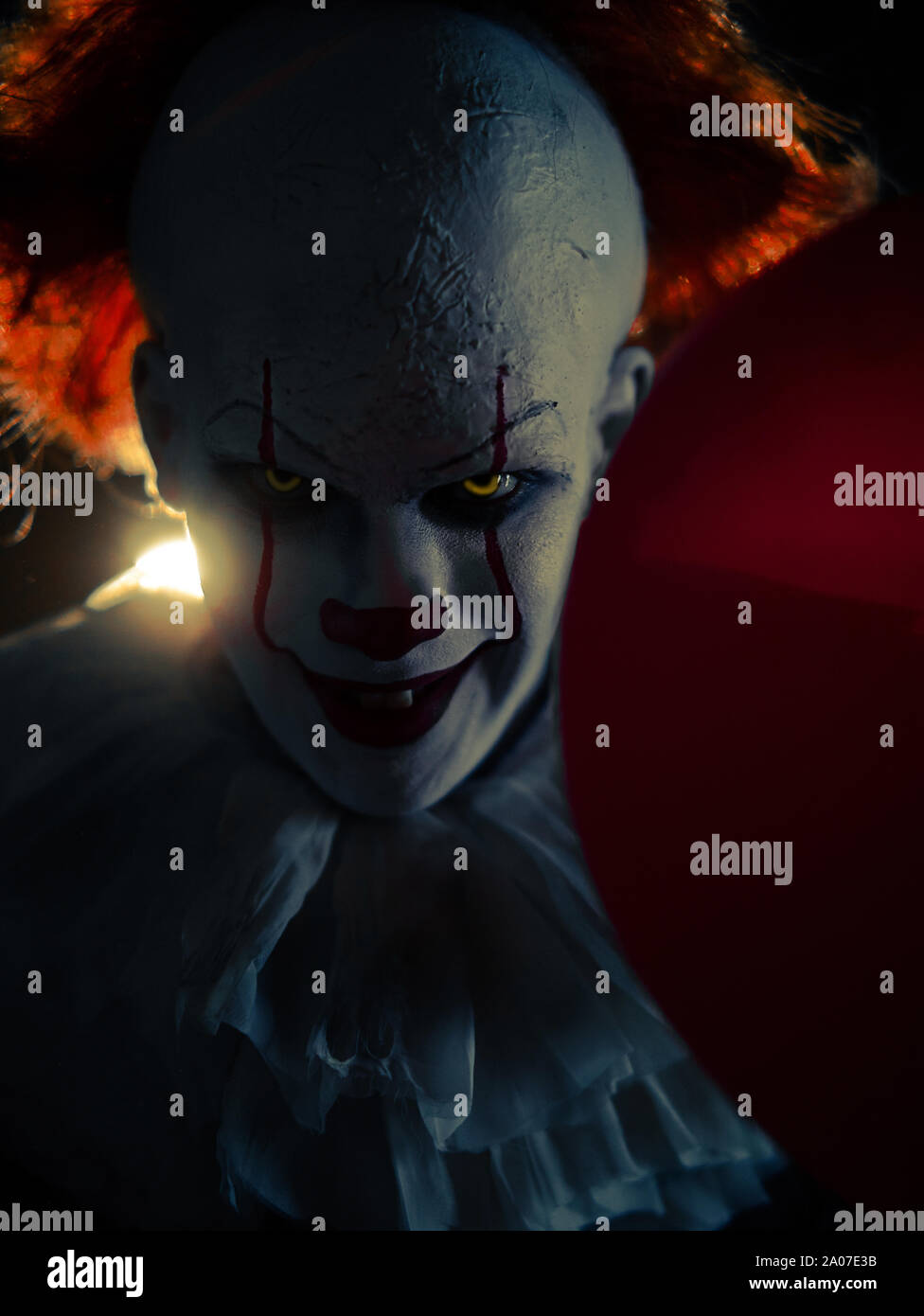 Portrait de clown au ballon rouge dans sa main avec rétro-éclairage. Banque D'Images