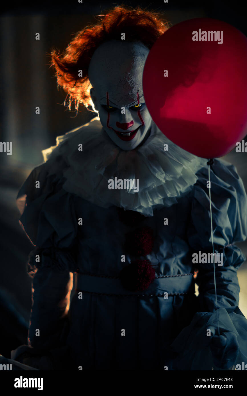 Portrait de clown au ballon rouge dans sa main avec rétro-éclairage. Banque D'Images