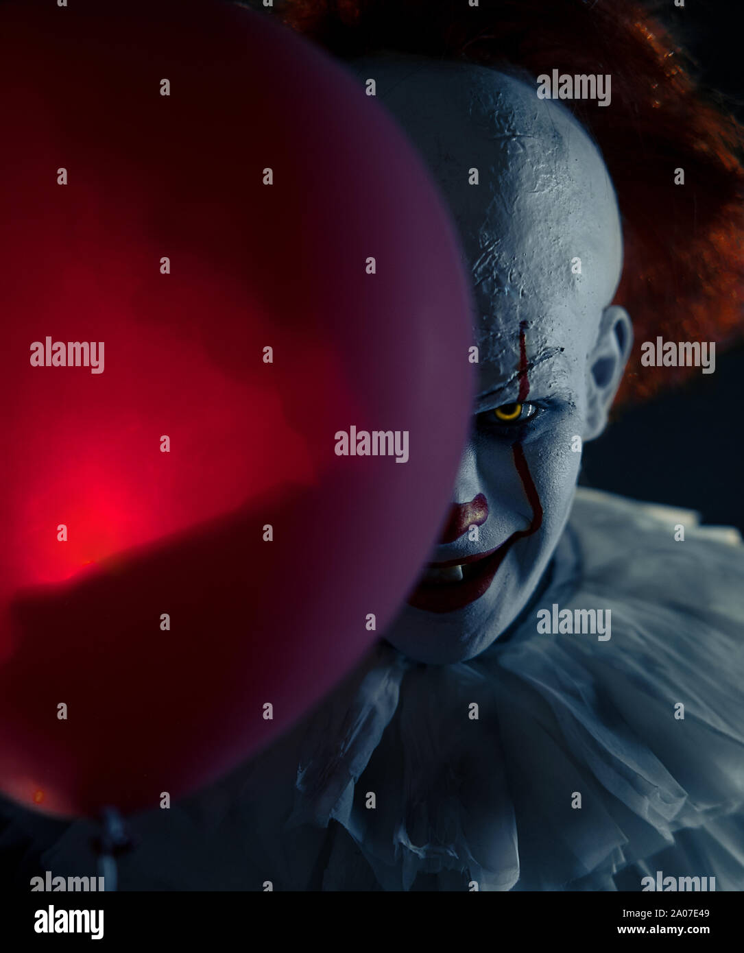 Portrait de clown au ballon rouge dans sa main avec rétro-éclairage. Banque D'Images
