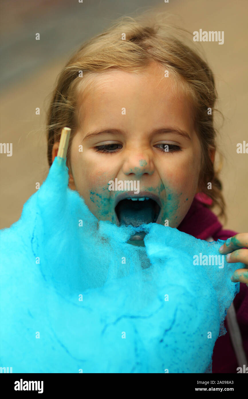 Closeup portrait of happy girl eating Cotton Candy bleu vif Banque D'Images