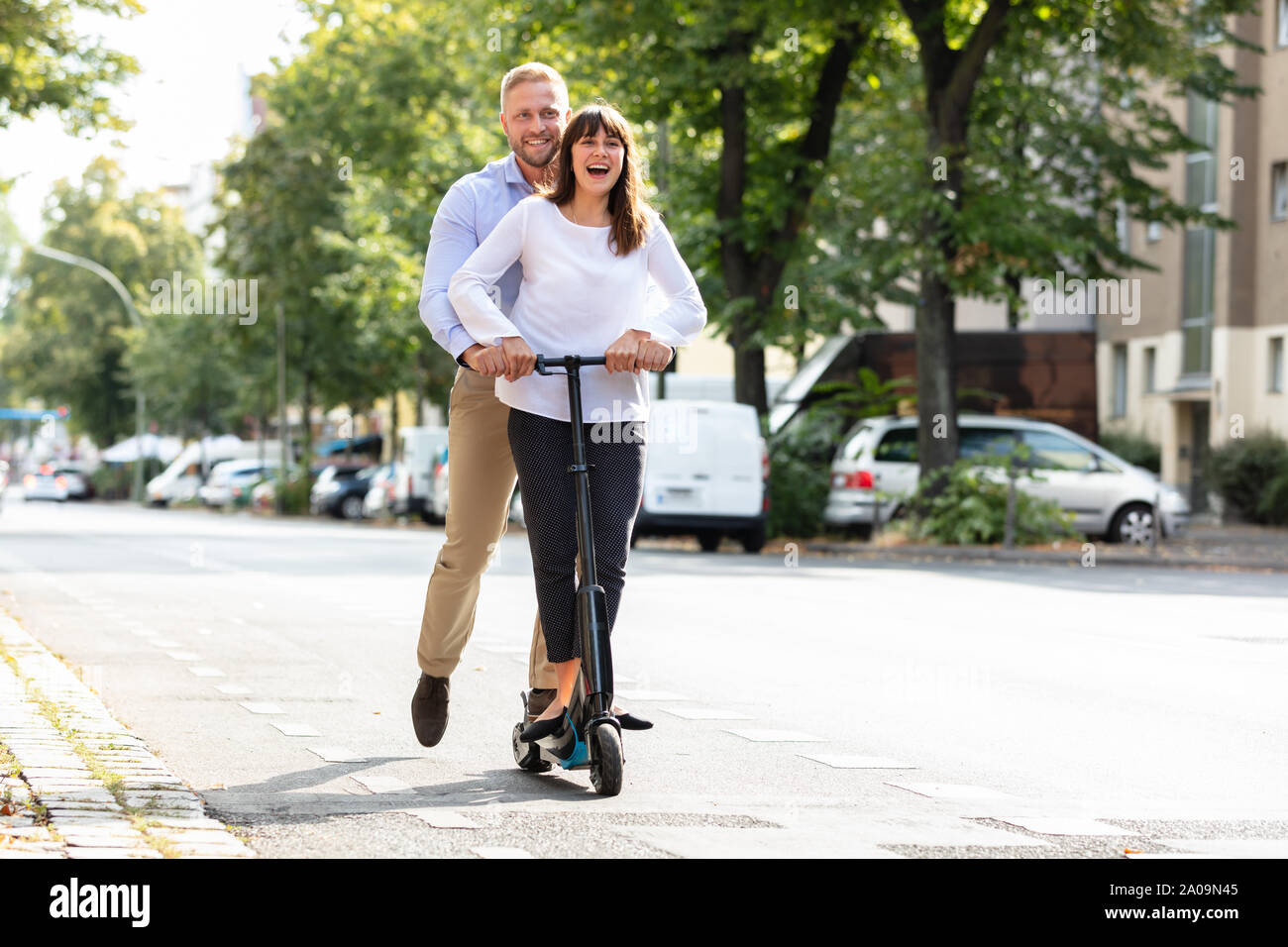 Portrait Of Happy Couple Riding sur scooter électrique sur la rue dans la ville Banque D'Images