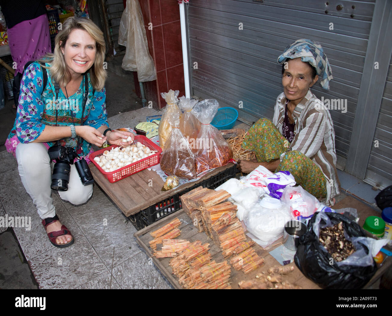 Caucasian Woman (libéré) avec Tradiional Femme birmane vendeur dans un marché de rue à Yangon Myanmar les deux Smilng à l'appareil photo. Banque D'Images