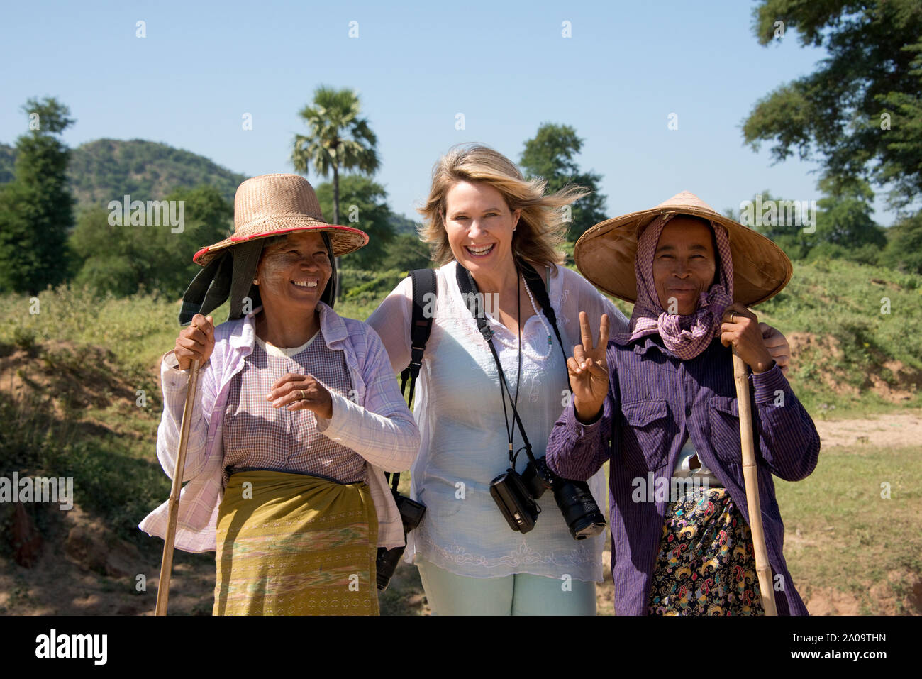 Une femme de race blanche (modèle) parution'posant avec deux birmans traditionnels Farm Women sur route près de Bagan Myanmar portant Thanaka un miroir pour Sun P Banque D'Images