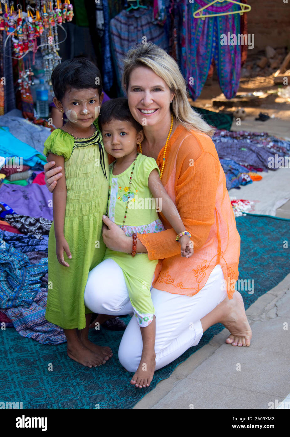 Une femme de race blanche (touristique) parution avec deux enfants birmans portant Thanaka dans maquillage marché plein air à Bagan Myanmar regardant la caméra. Banque D'Images