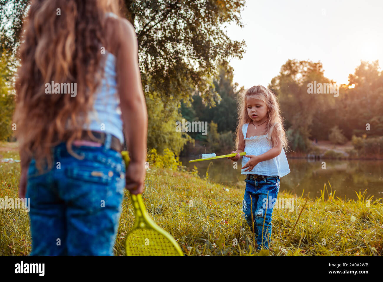 Le Badminton. Petite fille à jouer au badminton avec sœur en parc d'été. Les enfants s'amuser en plein air. Jeux de plein air pour les enfants Banque D'Images