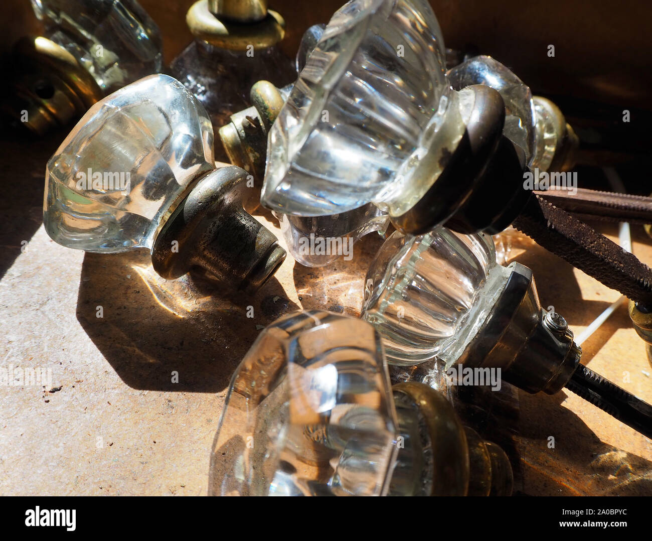 Une collection de meubles anciens couper le verre poignées du début du xxe siècle sur une table dans la lumière du soleil. Banque D'Images