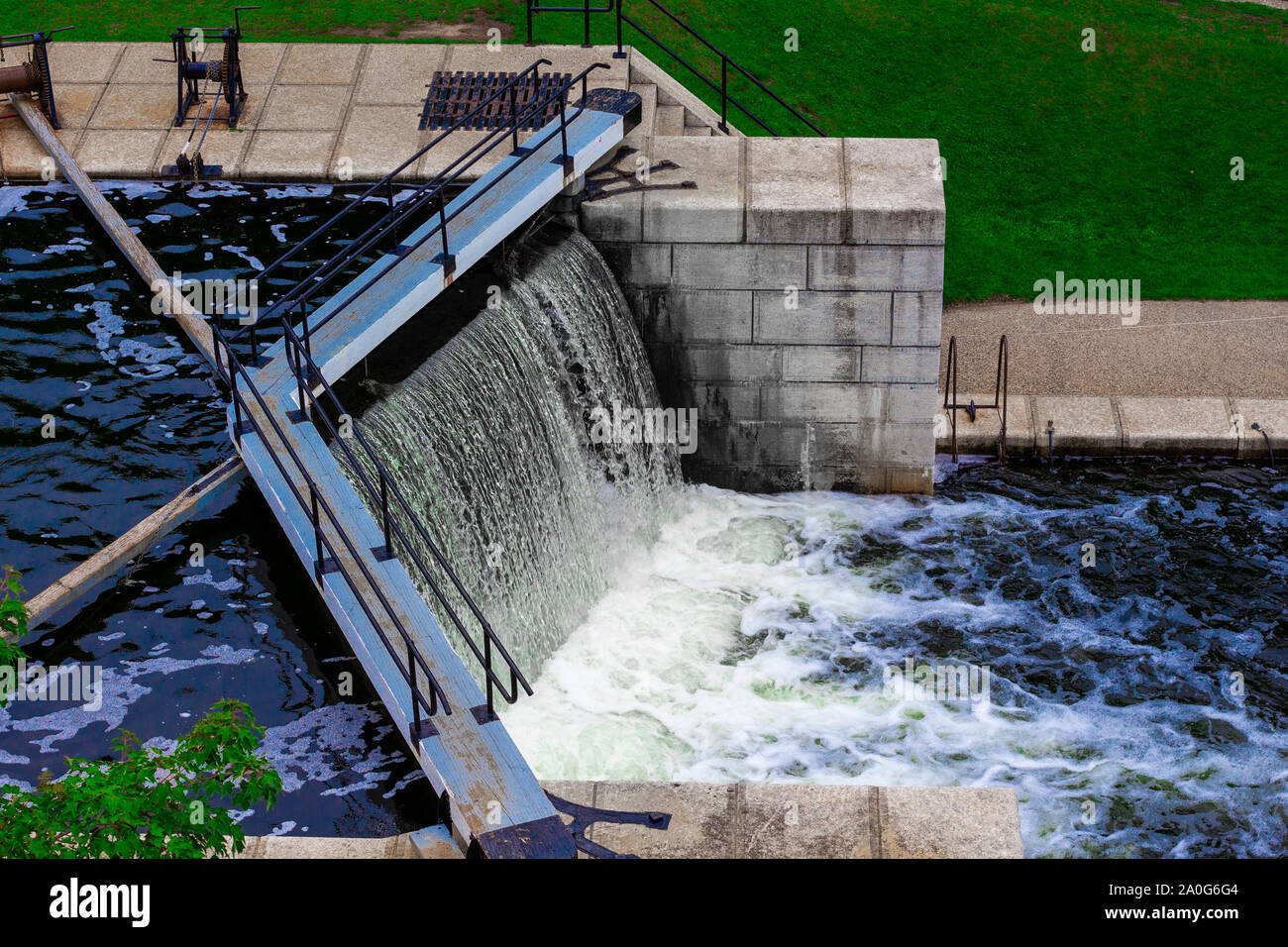 L'eau coule sur le bord d'un verrou dans un canal. Escaliers et murs en pierre les verrous de ligne, qui sont entourées d'un parc public. Banque D'Images