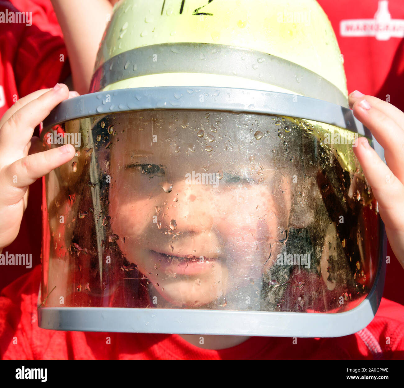 Langenreichenbach, Allemagne. Août 25, 2019. Les trois ans plus jeune 'firewoman" de "l'incendie volontaire mini brigade' dans un T-shirt avec un casque sur sa tête fièrement prend part à un cours de formation au centre de formation de Langenreichenbach dans le nord de la Saxe. Le camp dure deux jours et est supervisé par Leuschner et son épouse. (À l'extinction d'incendie dpa comme les grands - pompiers de l'enfant actif en Saxe) Credit : Waltraud Grubitzsch/dpa-Zentralbild/dpa/Alamy Live News Banque D'Images