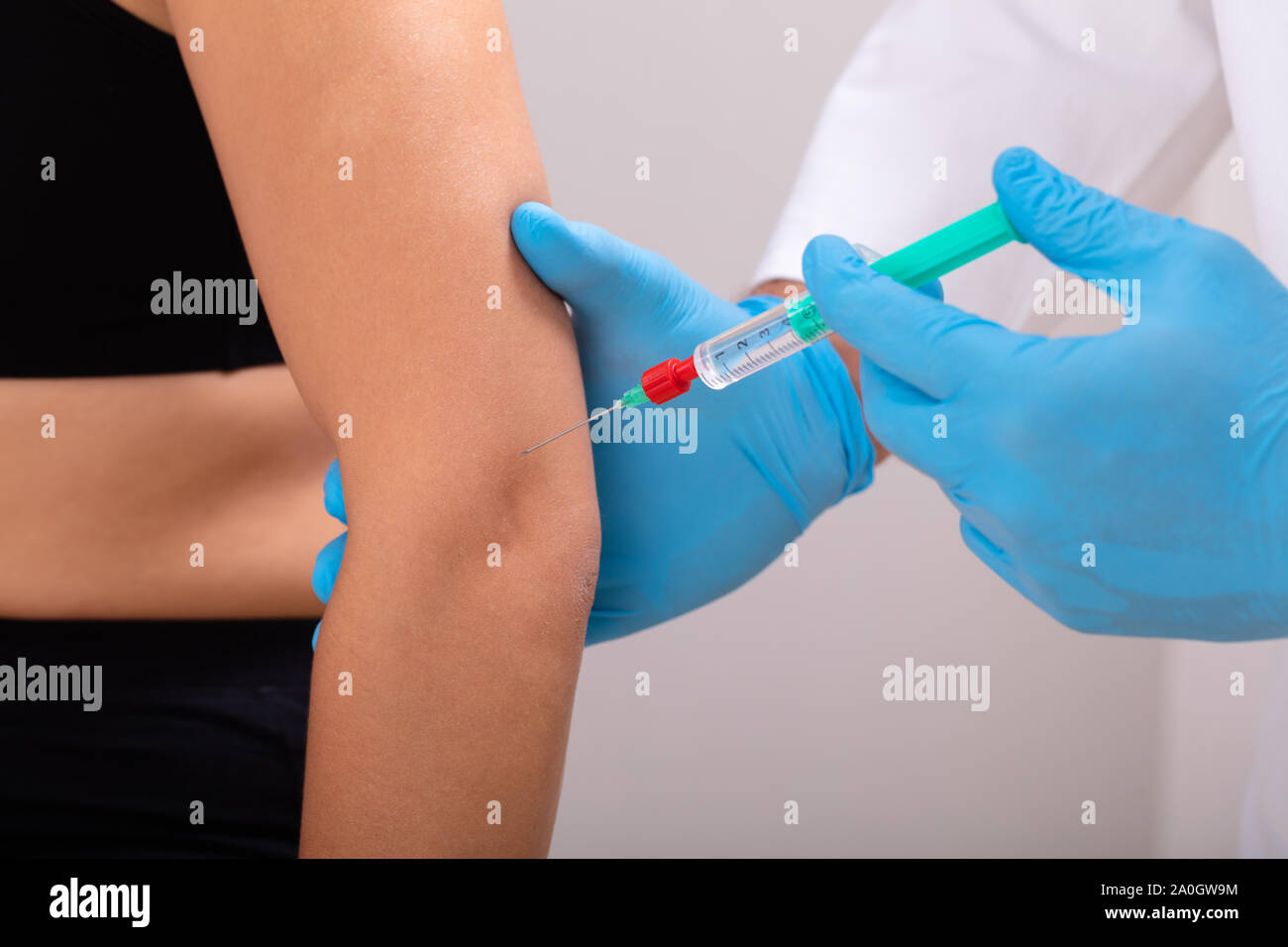 Close-up d'un cosmetologist portant des gants chirurgicaux bleu seringue de beauté donne sur le coude de la femme Banque D'Images