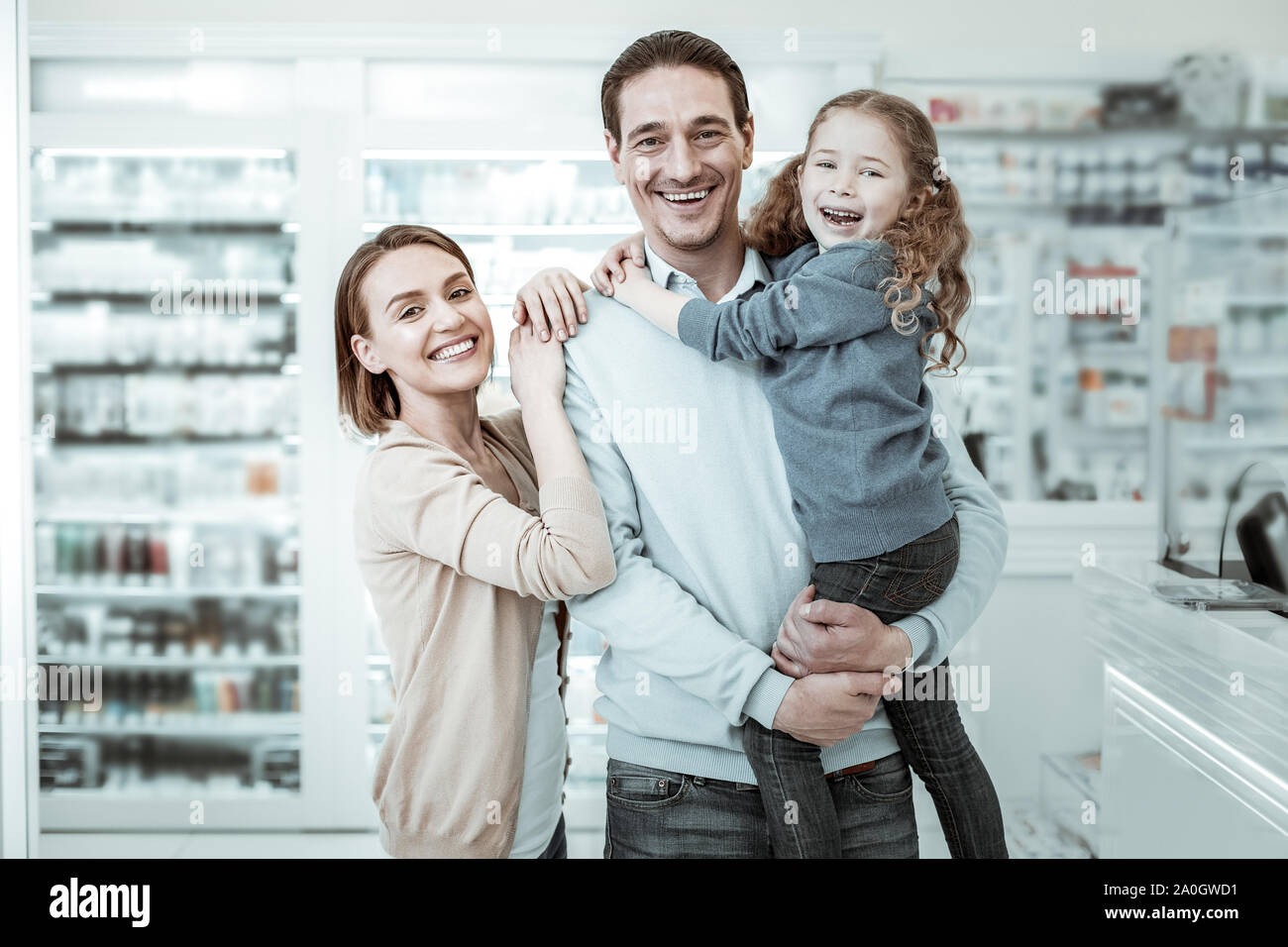 Un beamingly smiling family partager câlins à côté de la pharmacie commander Banque D'Images