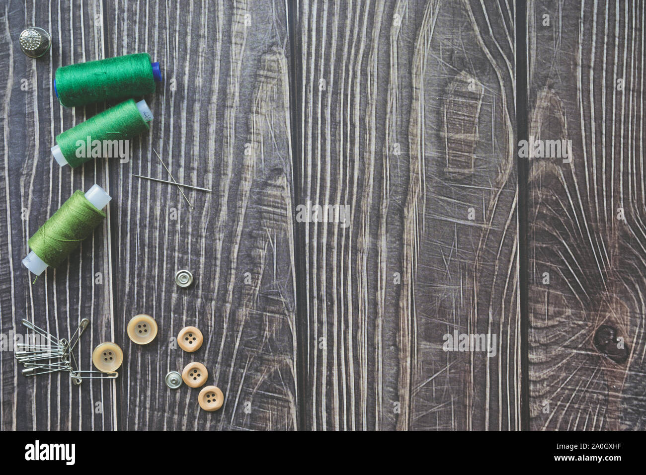 Accessoires de couture sur fond de bois sombre. Fils à coudre, Aiguille verte, les boutons et les axes. Vue de dessus, flatlay Banque D'Images