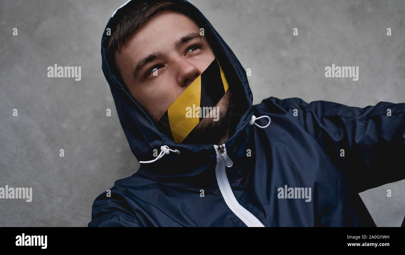 L'homme avec du ruban adhésif sur sa bouche. La bouche est scellée avec du ruban d'avertissement Banque D'Images