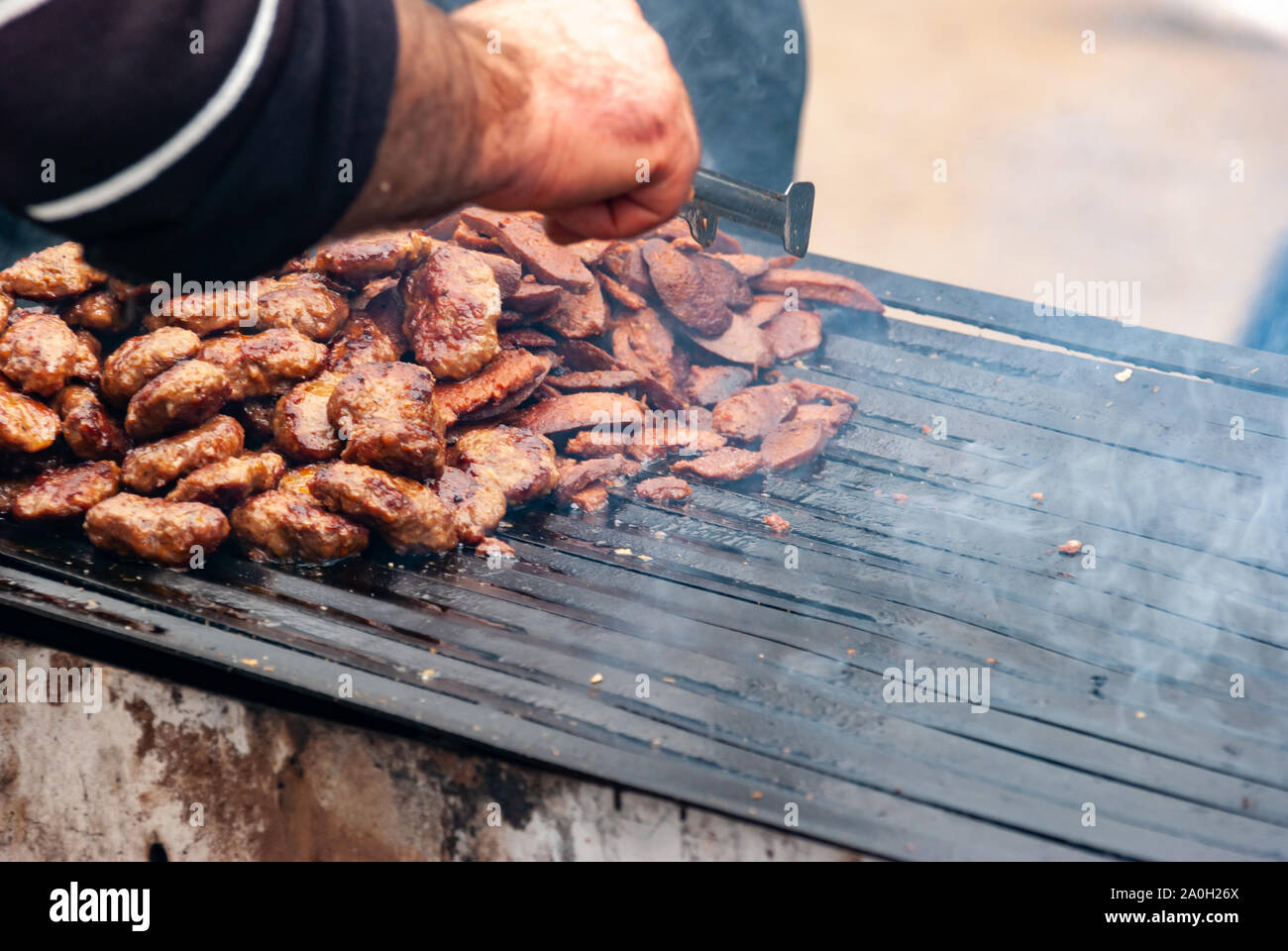 Man main cooking barbeque et des grillades de viande de chameau chameau au barbecue Wrestling festival. Banque D'Images