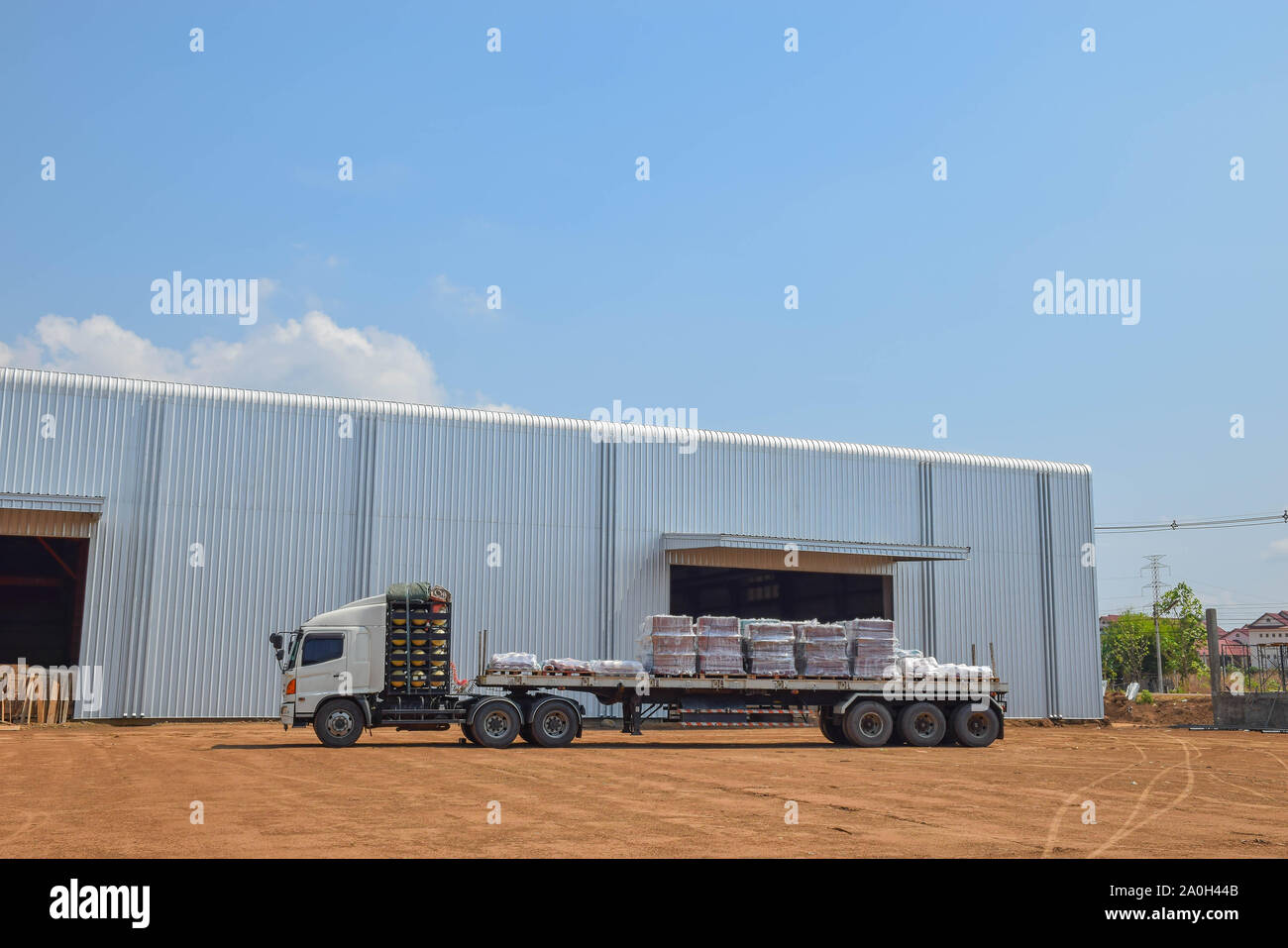 Camion remorque à l'entrepôt, entrepôt, stock, stocks, entrepôt bâtiment avec le ciel bleu fond de nuage. Banque D'Images