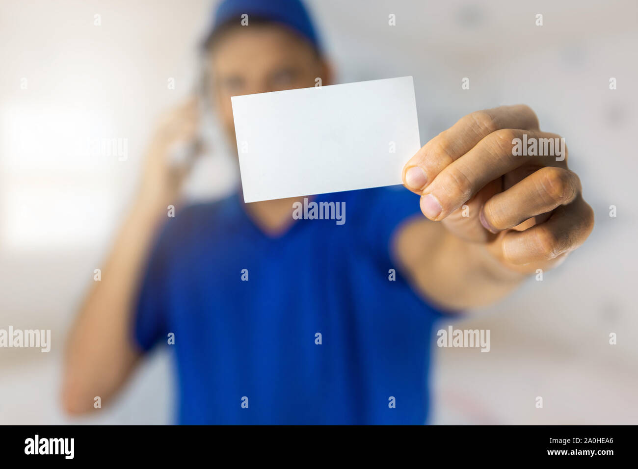 Handyman services - worker showing blank business card et effectuer un appel téléphonique Banque D'Images